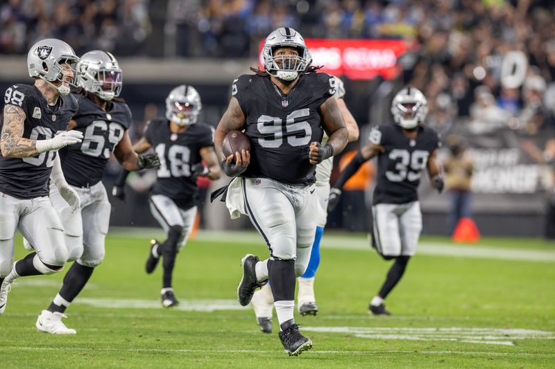 Las Vegas Raiders defensive tackle John Jenkins (95) scoops up a fumble and runs for a touchdown against the Los Angeles Chargers in an NFL football game, Thursday, Dec. 14, 2023, in Las Vegas, NV. Raiders defeat the Chargers 63-21. (AP Photo/Jeff Lewis)