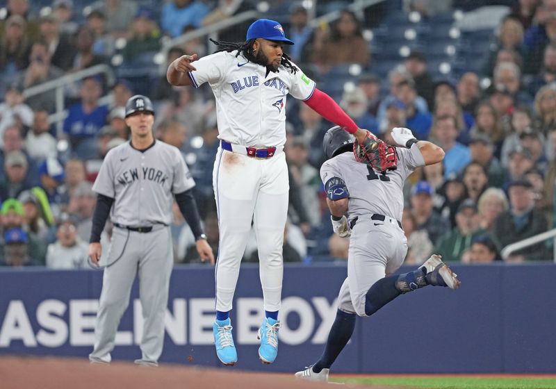 Apr 17, 2024; Toronto, Ontario, CAN; Toronto Blue Jays first base Vladimir Guerrero Jr. (27) tags out New York Yankees shortstop Anthony Volpe (11) at first base during the first inning at Rogers Centre. Mandatory Credit: Nick Turchiaro-USA TODAY Sports