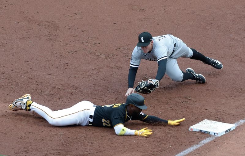 Apr 7, 2023; Pittsburgh, Pennsylvania, USA;  Pittsburgh Pirates designated hitter Andrew McCutchen (22) dives back into first base ahead of the tag attempt of Chicago White Sox first baseman Andrew Vaughn (25) to avoid a double play during the third inning at PNC Park. Mandatory Credit: Charles LeClaire-USA TODAY Sports