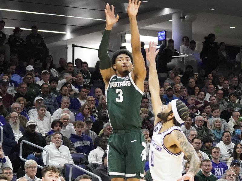 Jan 7, 2024; Evanston, Illinois, USA; Michigan State Spartans guard Jaden Akins (3) makes a three point basket over Northwestern Wildcats guard Boo Buie (0) during the first half at Welsh-Ryan Arena. Mandatory Credit: David Banks-USA TODAY Sports