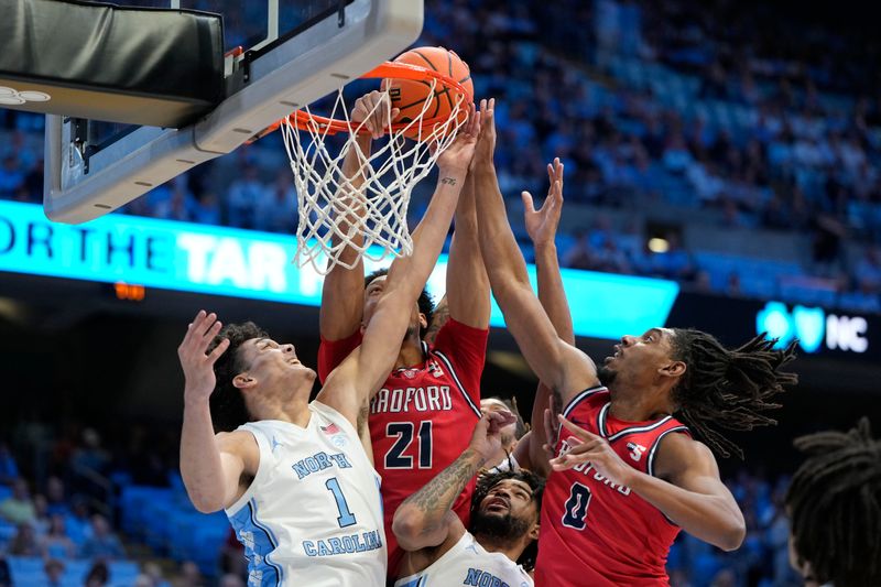 Nov 6, 2023; Chapel Hill, North Carolina, USA;  North Carolina Tar Heels forward Zayden High (1) and guard RJ Davis (4) fight for the ball around the rim with Radford Highlanders center D'Auntray Pierce (21) and forward Justin Archer (0) in the first half at Dean E. Smith Center. Mandatory Credit: Bob Donnan-USA TODAY Sports