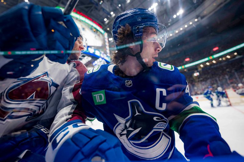 Mar 13, 2024; Vancouver, British Columbia, CAN; Vancouver Canucks defenseman Quinn Hughes (43) checks Colorado Avalanche forward Brandon Duhaime (12) in the first period at Rogers Arena. Mandatory Credit: Bob Frid-USA TODAY Sports