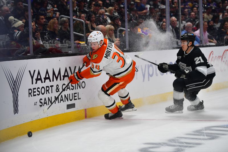 Apr 10, 2025; Los Angeles, California, USA; Anaheim Ducks defenseman Pavel Mintyukov (34) moves the puck ahead of Los Angeles Kings defenseman Jordan Spence (21) during the first period at Crypto.com Arena. Mandatory Credit: Gary A. Vasquez-Imagn Images