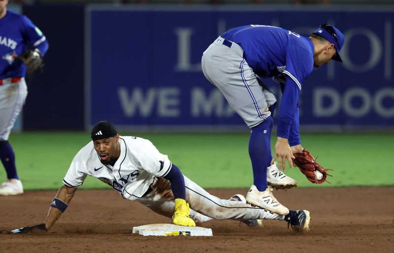 Sep 16, 2025; St. Petersburg, Florida, USA;  Tampa Bay Rays left fielder Chandler Simpson (14) steals second base as Toronto Blue Jays shortstop Andres Gimenez (0) attempts to tag him out during the third inning at George M. Steinbrenner Field. Mandatory Credit: Kim Klement Neitzel-Imagn Images