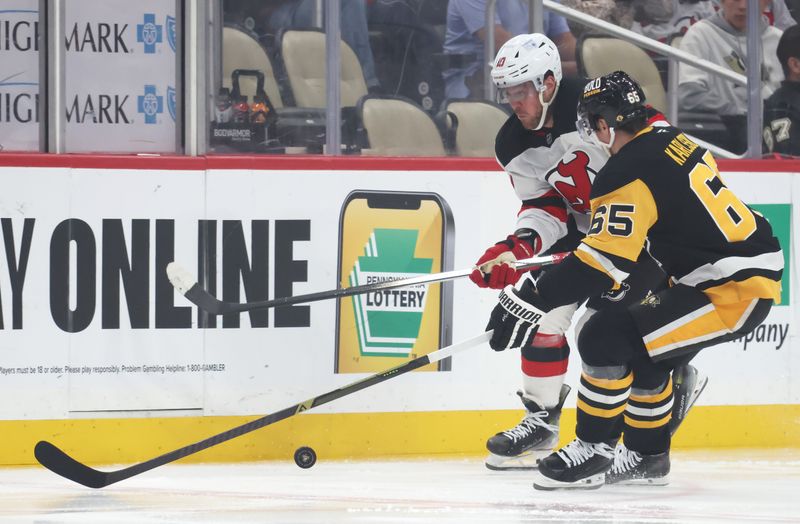 Mar 15, 2025; Pittsburgh, Pennsylvania, USA;  New Jersey Devils right wing Daniel Sprong (10) moves the puck against Pittsburgh Penguins defenseman Erik Karlsson (65) during the third period at PPG Paints Arena. Mandatory Credit: Charles LeClaire-Imagn Images