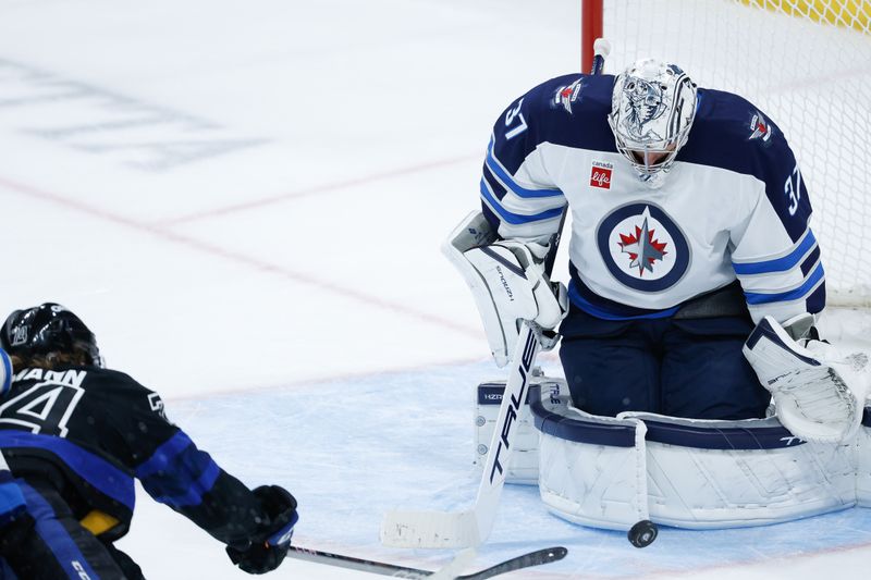 Oct 28, 2024; Winnipeg, Manitoba, CAN;  Winnipeg Jets goalie Connor Hellebuyck (37) makes a save on a shot as Toronto Maple Leafs forward Bobby McMann (74) looks for a rebound during the third period at Canada Life Centre. Mandatory Credit: Terrence Lee-Imagn Images