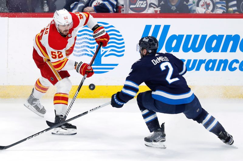 iApr 4, 2024; Winnipeg, Manitoba, CAN; Calgary Flames defenseman MacKenzie Weegar (52) flips the puck past Winnipeg Jets defenseman Dylan DeMelo (2) in the third period at Canada Life Centre. Mandatory Credit: James Carey Lauder-USA TODAY Sports