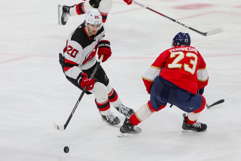 Jan 13, 2024; Sunrise, Florida, USA; New Jersey Devils center Michael McLeod (20) moves the puck past Florida Panthers center Carter Verhaeghe (23) during the third period at Amerant Bank Arena. Mandatory Credit: Sam Navarro-USA TODAY Sports