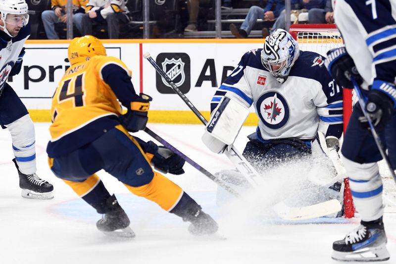 Apr 9, 2024; Nashville, Tennessee, USA; Nashville Predators defenseman Spencer Stastney (24) scores a goal against Winnipeg Jets goaltender Connor Hellebuyck (37) during the third period at Bridgestone Arena. Mandatory Credit: Christopher Hanewinckel-USA TODAY Sports