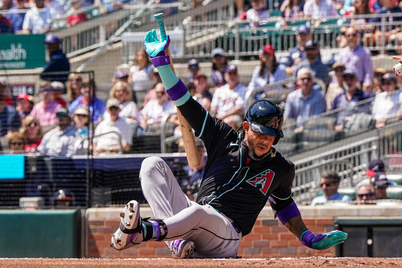 Apr 7, 2024; Cumberland, Georgia, USA; Arizona Diamondbacks second baseman Ketel Marte (4) falls after swinging at a pitch against the Atlanta Braves during the first inning at Truist Park. Mandatory Credit: Dale Zanine-USA TODAY Sports