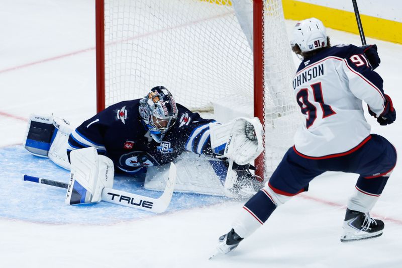 Nov 18, 2025; Winnipeg, Manitoba, CAN;  Winnipeg Jets goalie Eric Comrie (1) stops Columbus Blue Jackets forward Kent Johnson (91) during the third period at Canada Life Centre. Mandatory Credit: Terrence Lee-Imagn Images