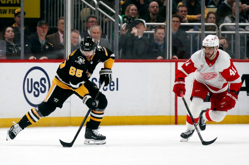 Apr 11, 2024; Pittsburgh, Pennsylvania, USA; Pittsburgh Penguins defenseman Erik Karlsson (65) moves the puck against Detroit Red Wings defenseman Shayne Gostisbehere (41) in overtime at PPG Paints Arena. Pittsburgh won 6-5 in overtime.Mandatory Credit: Charles LeClaire-USA TODAY Sports