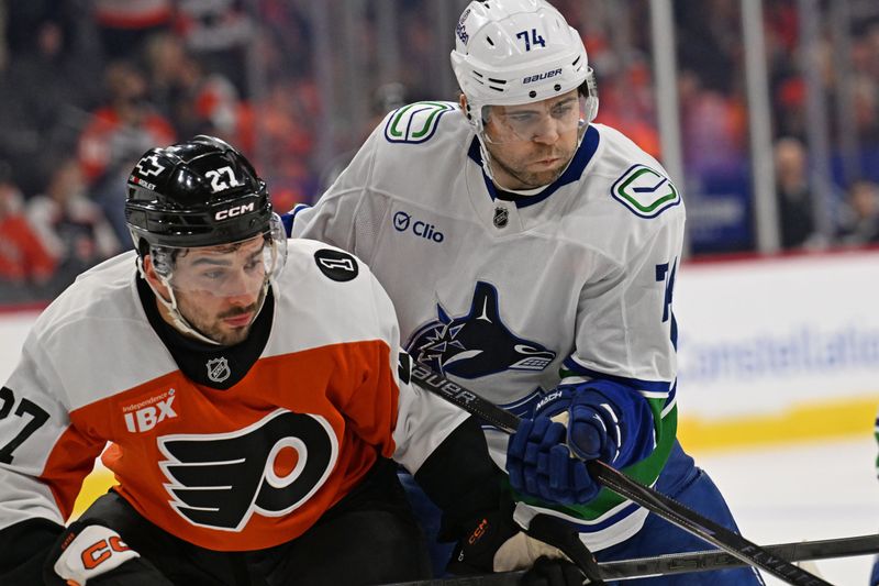 Dec 22, 2025; Philadelphia, Pennsylvania, USA; Philadelphia Flyers left wing Noah Cates (27) and Vancouver Canucks left wing Jake Debrusk (74) battle for position during the first period at Xfinity Mobile Arena. Mandatory Credit: Eric Hartline-Imagn Images