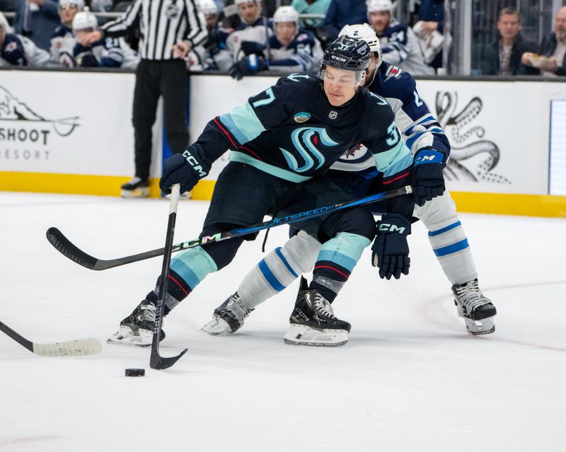 Oct 24, 2024; Seattle, Washington, USA;  Seattle Kraken forward Yanni Gourde (37) skates against Winnipeg Jets defenseman Dylan DeMelo (2) during the first period at Climate Pledge Arena. Mandatory Credit: Stephen Brashear-Imagn Images