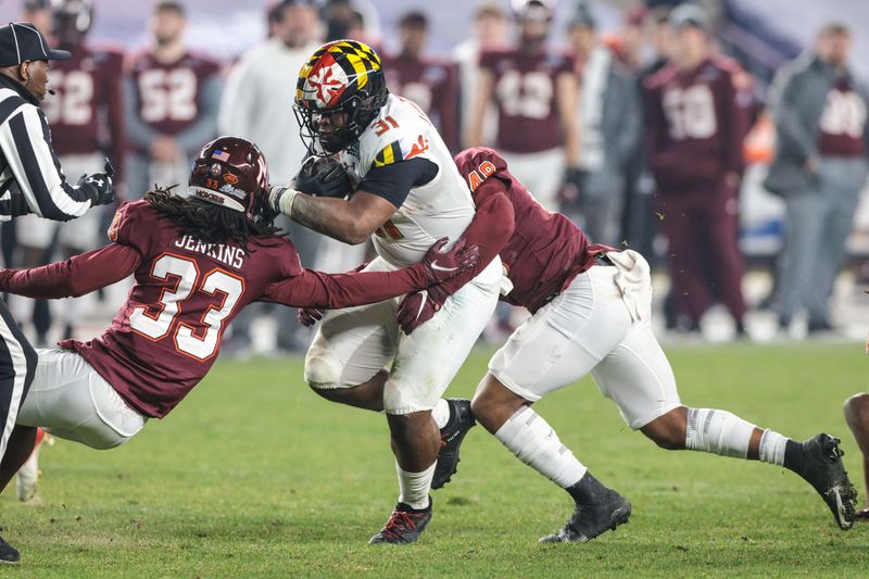 Dec 29, 2021; New York, NY, USA; Maryland Terrapins running back Antwaine Littleton II (31) runs the ball as Virginia Tech Hokies defensive back Keonta Jenkins (33) and defensive back Jabari Parker (28) tackle during the second half of the 2021 Pinstripe Bowl at Yankee Stadium. Mandatory Credit: Vincent Carchietta-USA TODAY Sports