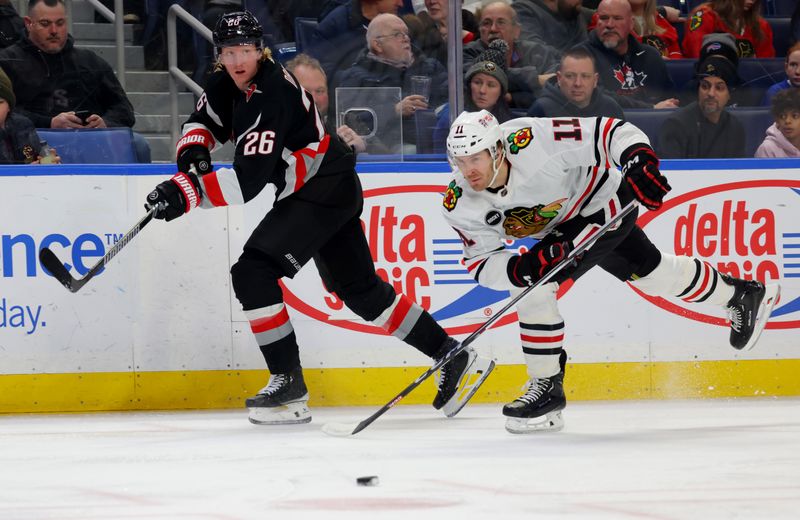 Jan 18, 2024; Buffalo, New York, USA;  Chicago Blackhawks right wing Taylor Raddysh (11) tries to block a pass by Buffalo Sabres defenseman Rasmus Dahlin (26) during the first period at KeyBank Center. Mandatory Credit: Timothy T. Ludwig-USA TODAY Sports