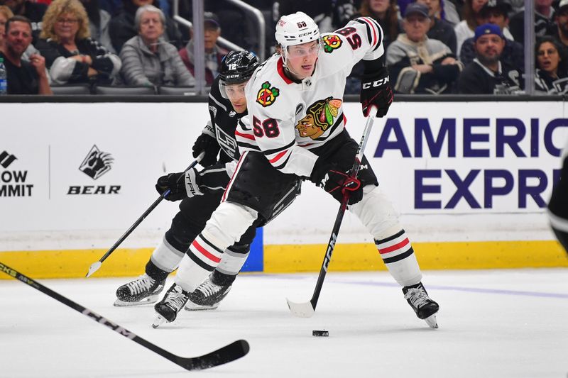 Apr 18, 2024; Los Angeles, California, USA; Chicago Blackhawks right wing MacKenzie Entwistle (58) moves the puck ahead of Los Angeles Kings left wing Trevor Moore (12) during the third period at Crypto.com Arena. Mandatory Credit: Gary A. Vasquez-USA TODAY Sports