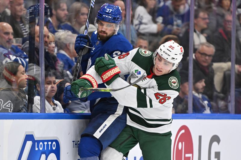 Oct 14, 2023; Toronto, Ontario, CAN;   Minnesota Wild forward Connor Dewar (26) bodychecks Toronto Maple Leafs defenseman Timothy Liljegren (37) in the second period at Scotiabank Arena. Mandatory Credit: Dan Hamilton-USA TODAY Sports