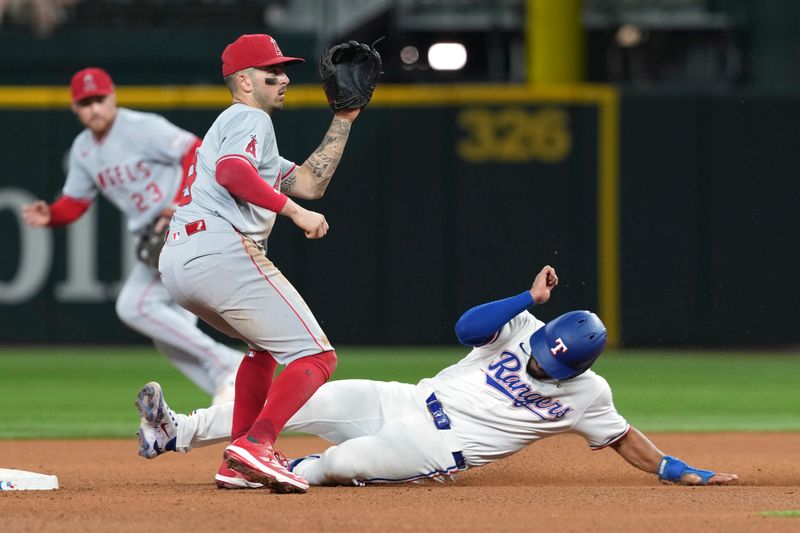 Sep 7, 2024; Arlington, Texas, USA; Texas Rangers second baseman Marcus Semien (2) steals second base ahead of the throw to Los Angeles Angels shortstop Zach Neto (9) during the seventh inning at Globe Life Field. Mandatory Credit: Jim Cowsert-Imagn Images