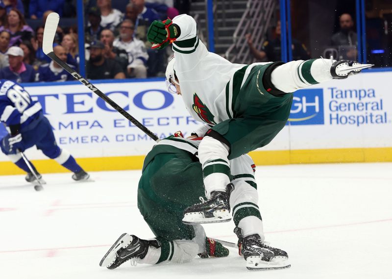 Oct 24, 2024; Tampa, Florida, USA;Minnesota Wild left wing Liam Ohgren (28) and center Marat Khusnutdinov (22) collide into each other against the Tampa Bay Lightning during the second period at Amalie Arena. Mandatory Credit: Kim Klement Neitzel-Imagn Images