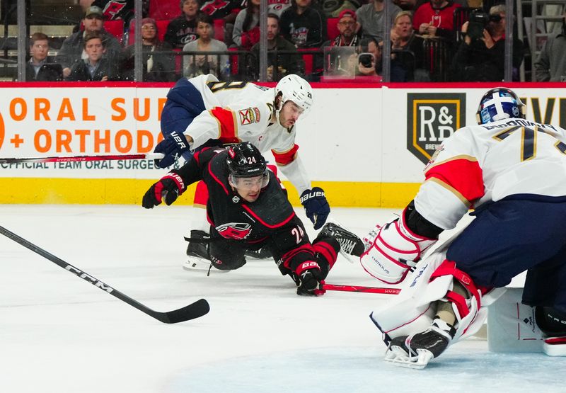 Mar 14, 2024; Raleigh, North Carolina, USA; Carolina Hurricanes center Seth Jarvis (24) is held by Florida Panthers defenseman Josh Mahura (28) during the first period t PNC Arena. Mandatory Credit: James Guillory-USA TODAY Sports