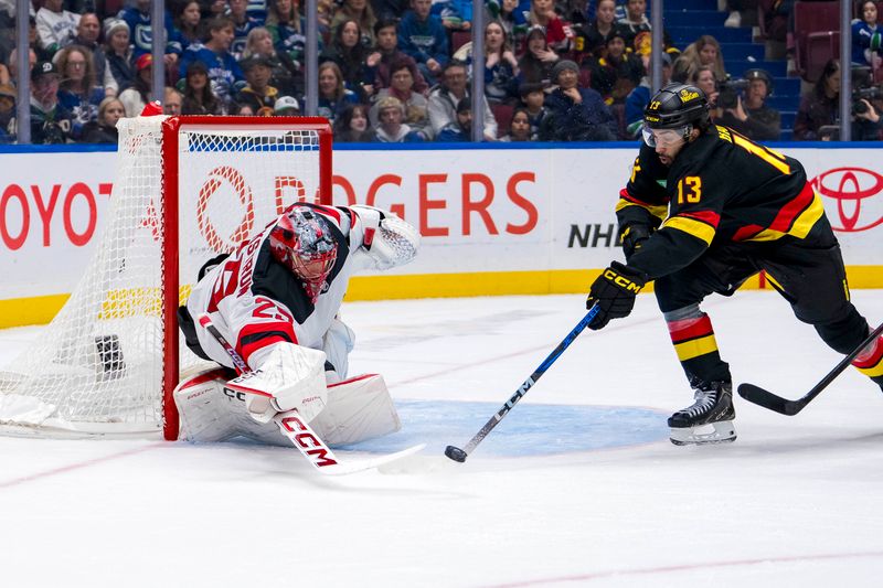 Oct 30, 2024; Vancouver, British Columbia, CAN; New Jersey Devils goalie Jacob Markstrom (25) poke checks Vancouver Canucks forward Arshdeep Bains (13) during the second period at Rogers Arena. Mandatory Credit: Bob Frid-Imagn Images