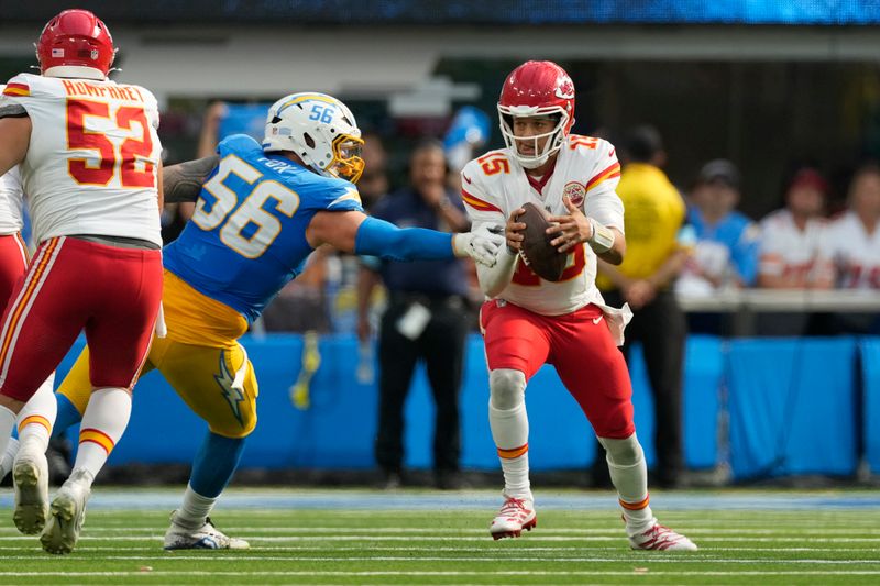 Kansas City Chiefs quarterback Patrick Mahomes, right, scrambles away from Los Angeles Chargers defensive lineman Morgan Fox (56) during the second half of an NFL football game Sunday, Sept. 29, 2024, in Inglewood, Calif. (AP Photo/Ashley Landis)