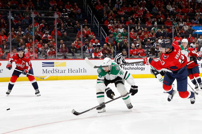 Oct 17, 2024; Washington, District of Columbia, USA; Washington Capitals left wing Jakub Vrana (13) loses his balance while shooting the puck as Dallas Stars defenseman Ilya Lyubushkin (46) in the third period at Capital One Arena. Mandatory Credit: Geoff Burke-Imagn Images