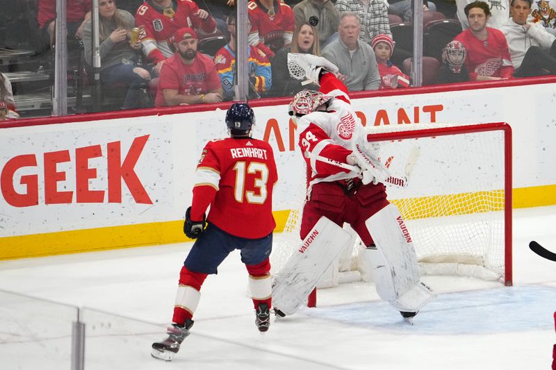 Jan 17, 2024; Sunrise, Florida, USA; Detroit Red Wings goaltender Alex Lyon (34) reaches for the puck in front of Florida Panthers center Sam Reinhart (13) during the third period at Amerant Bank Arena. Mandatory Credit: Jasen Vinlove-USA TODAY Sports