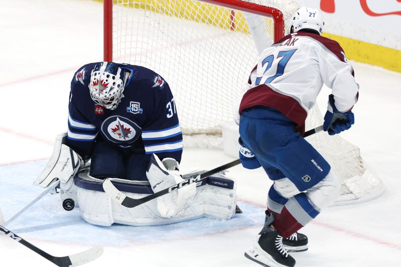 Mar 26, 2026; Winnipeg, Manitoba, CAN; Winnipeg Jets goaltender Connor Hellebuyck (37) blocks a shot by Colorado Avalanche defenseman Brett Kulak (27) in the third period at Canada Life Centre. Mandatory Credit: James Carey Lauder-Imagn Images