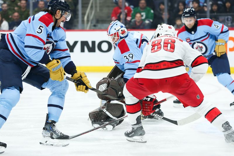 Dec 4, 2023; Winnipeg, Manitoba, CAN;   Winnipeg Jets defenseman Brenden Dillon (5) checks Carolina Hurricanes forward Teuvo Teravainen (86) in front of Winnipeg Jets goalie Laurent Boissoit (39) during the first period at Canada Life Centre. Mandatory Credit: Terrence Lee-USA TODAY Sports