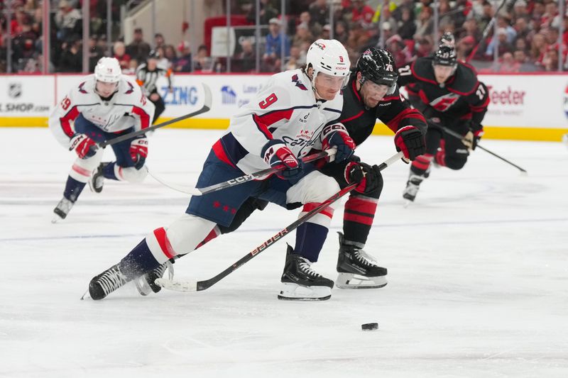 Nov 11, 2025; Raleigh, North Carolina, USA; Washington Capitals right wing Ryan Leonard (9) battles Carolina Hurricanes defenseman Sean Walker (26) for the puck during the second period at Lenovo Center. Mandatory Credit: James Guillory-Imagn Images
