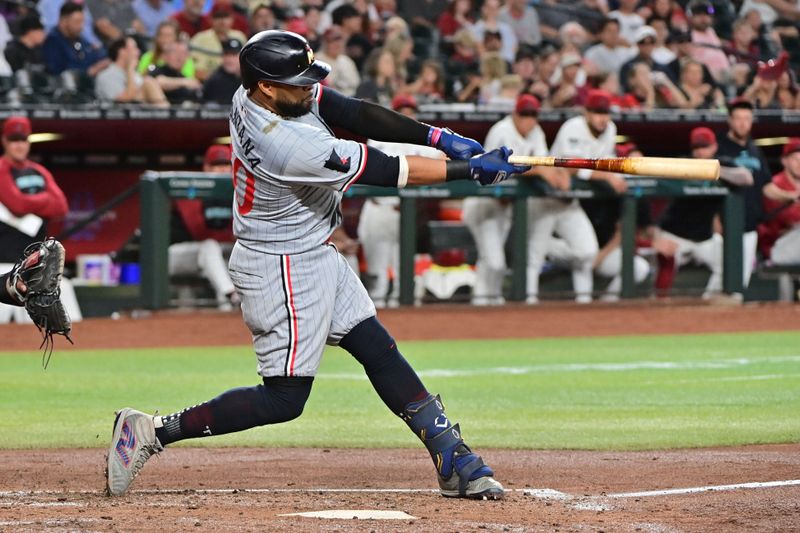 Jun 27, 2024; Phoenix, Arizona, USA;  Minnesota Twins first base Carlos Santana (30) hits an RBI double in the second inning against the Arizona Diamondbacks at Chase Field. Mandatory Credit: Matt Kartozian-USA TODAY Sports