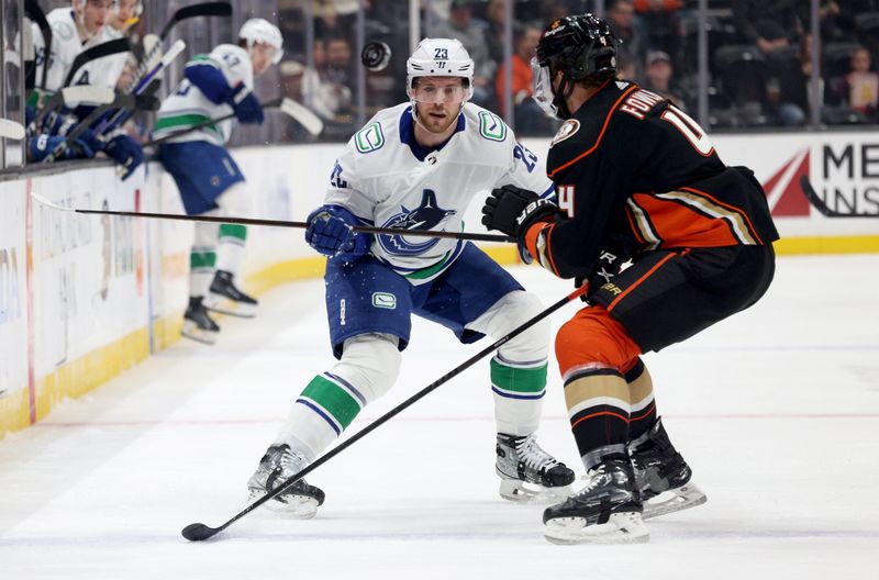 Mar 3, 2024; Anaheim, California, USA; Vancouver Canucks center Elias Lindholm (23) and Anaheim Ducks defenseman Cam Fowler (4) battle for the puck during the first period at Honda Center. Mandatory Credit: Jason Parkhurst-USA TODAY Sports