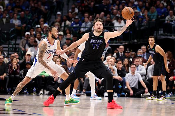 DALLAS, TEXAS - DECEMBER 20: Luka Doncic #77 of the Dallas Mavericks catches a pass while defended by Amir Coffey #7 of the LA Clippers in the second half at American Airlines Center on December 20, 2023 in Dallas, Texas. NOTE TO USER: User expressly acknowledges and agrees that, by downloading and or using this photograph, User is consenting to the terms and conditions of the Getty Images License Agreement. (Photo by Tim Heitman/Getty Images)