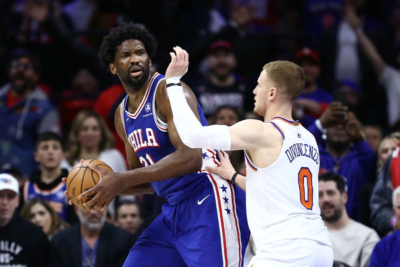 PHILADELPHIA, PENNSYLVANIA - APRIL 25: Joel Embiid #21 of the Philadelphia 76ers is guarded by Donte DiVincenzo #0 of the New York Knicks during the fourth quarter of game three of the Eastern Conference First Round Playoffs at the Wells Fargo Center on April 25, 2024 in Philadelphia, Pennsylvania. NOTE TO USER: User expressly acknowledges and agrees that, by downloading and/or using this Photograph, user is consenting to the terms and conditions of the Getty Images License Agreement. (Photo by Tim Nwachukwu/Getty Images)