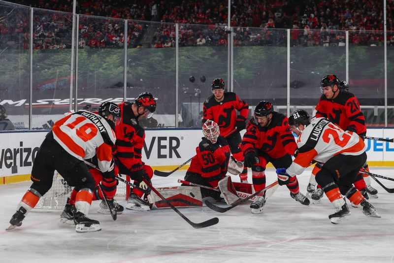 Feb 17, 2024; East Rutherford, New Jersey, USA; New Jersey Devils goaltender Nico Daws (50) makes a save on Philadelphia Flyers center Scott Laughton (21) during the third period in a Stadium Series ice hockey game at MetLife Stadium. Mandatory Credit: Ed Mulholland-USA TODAY Sports