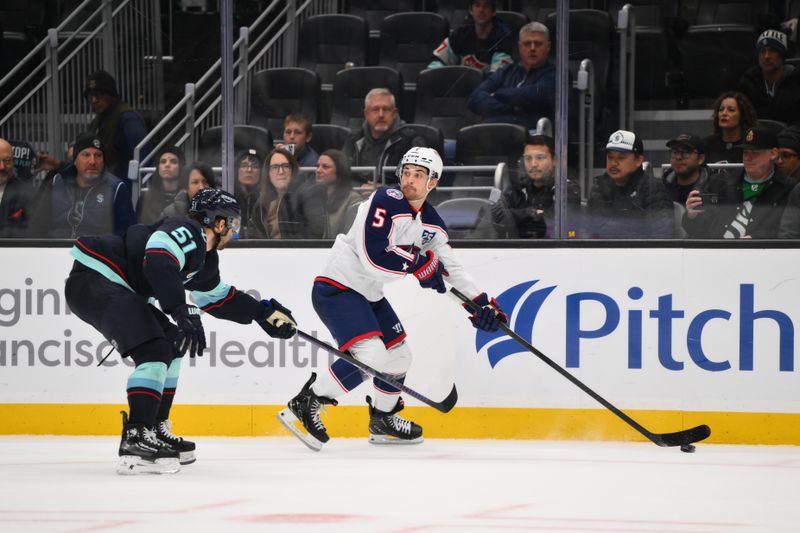 Nov 11, 2025; Seattle, Washington, USA; Columbus Blue Jackets defenseman Denton Mateychuk (5) plays the puck while defended by Seattle Kraken center Shane Wright (51) during overtime at Climate Pledge Arena. Mandatory Credit: Steven Bisig-Imagn Images