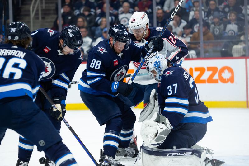 Jan 9, 2024; Winnipeg, Manitoba, CAN; Winnipeg Jets defenseman Nate Schmidt (88), forward Dominic Toninato (21), and goaltender Connor Hellebuyck (37) look for the puck to defend against Columbus Blue Jackets forward Mathieu Olivier (24) during the first period at Canada Life Centre. Mandatory Credit: Terrence Lee-USA TODAY Sports