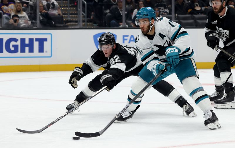 Oct 24, 2024; Los Angeles, California, USA; San Jose Sharks center Luke Kunin (11) moves the puck against Los Angeles Kings defenseman Brandt Clarke (92) during the third period at Crypto.com Arena. Mandatory Credit: Jason Parkhurst-Imagn Images