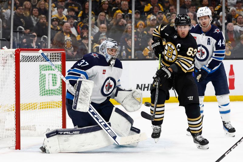 Jan 22, 2024; Boston, Massachusetts, USA; Boston Bruins left wing Brad Marchand (63) tries to deflect a shot on Winnipeg Jets goaltender Connor Hellebuyck (37) during the second period at TD Garden. Mandatory Credit: Winslow Townson-USA TODAY Sports