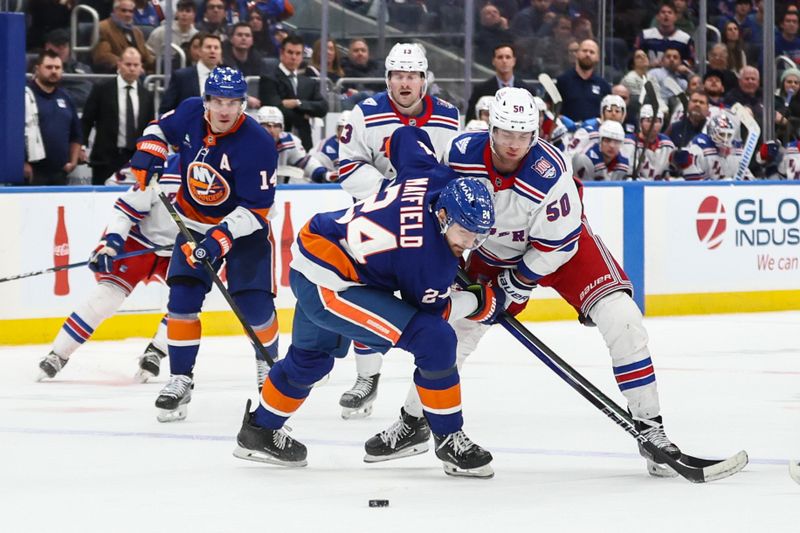 Dec 27, 2025; Elmont, New York, USA;  New York Islanders defenseman Scott Mayfield (24) and New York Rangers left wing Will Cuylle (50) battle for control of the puck in the third period at UBS Arena. Mandatory Credit: Wendell Cruz-Imagn Images