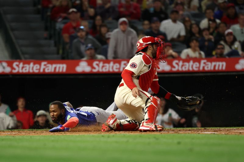 May 7, 2025; Anaheim, California, USA;  Toronto Blue Jays first baseman Vladimir Guerrero Jr. (27) scores under the tag of Los Angeles Angels catcher Travis d'Arnaud (25) on a single by designated hitter Anthony Santander (25, not pictured) during the sixth inning at Angel Stadium. Mandatory Credit: Kiyoshi Mio-Imagn Images