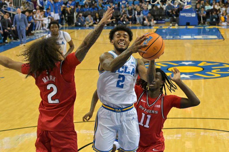 Feb 3, 2026; Los Angeles, California, USA;  UCLA Bruins guard Donovan Dent (2) is defended by Rutgers Scarlet Knights guard Lino Mark (2) and Rutgers Scarlet Knights forward Chris Nwuli (11) as he drives for a basket in the first half at Pauley Pavilion presented by Wescom Financial. Mandatory Credit: Jayne Kamin-Oncea-Imagn Images