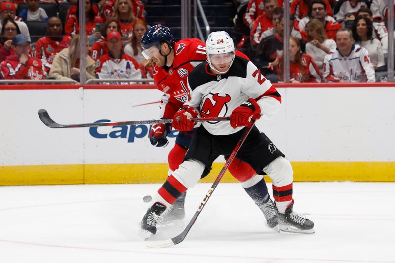 Oct 12, 2024; Washington, District of Columbia, USA; New Jersey Devils defenseman Seamus Casey (24) and Washington Capitals right wing Taylor Raddysh (16) battle for the puck in the first period at Capital One Arena. Mandatory Credit: Geoff Burke-Imagn Images