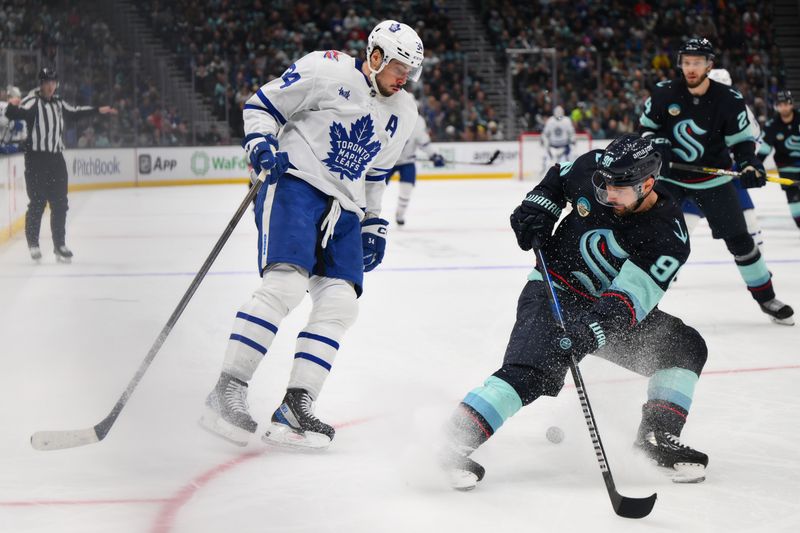 Jan 21, 2024; Seattle, Washington, USA; Toronto Maple Leafs center Auston Matthews (34) passes the puck behind Seattle Kraken left wing Tomas Tatar (90) during the third period at Climate Pledge Arena. Mandatory Credit: Steven Bisig-USA TODAY Sports