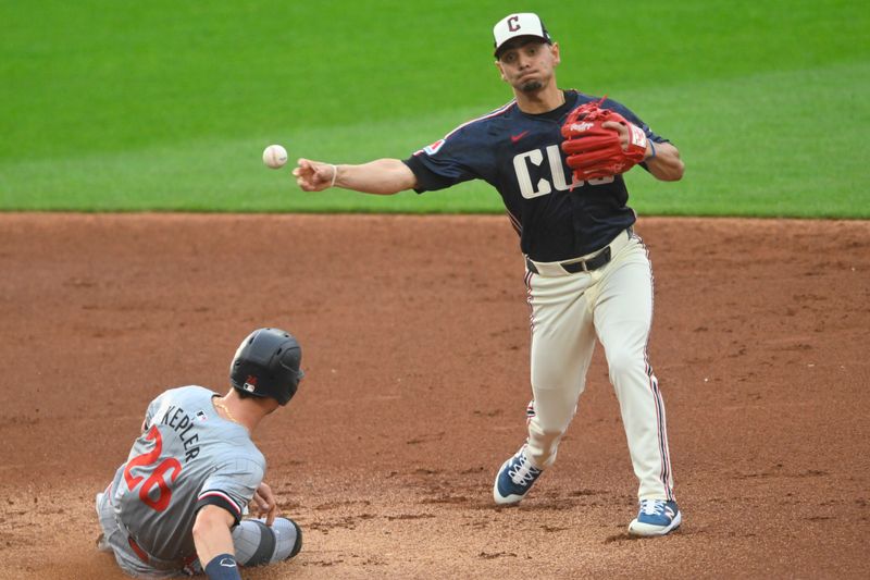 May 17, 2024; Cleveland, Ohio, USA; Cleveland Guardians second baseman Andres Gimenez (0) turns a double play beside Minnesota Twins right fielder Max Kepler (26) in the second inning at Progressive Field. Mandatory Credit: David Richard-USA TODAY Sports