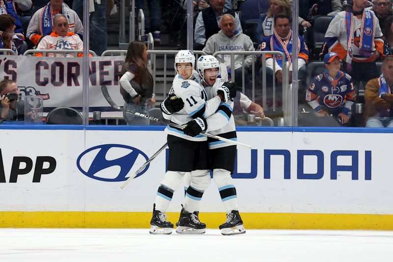 Oct 10, 2024; Elmont, New York, USA; Utah Hockey Club right wing Dylan Guenther (11) celebrates his game winning overtime goal against the New York Islanders with defenseman Sean Durzi (50) at UBS Arena. Mandatory Credit: Brad Penner-Imagn Images