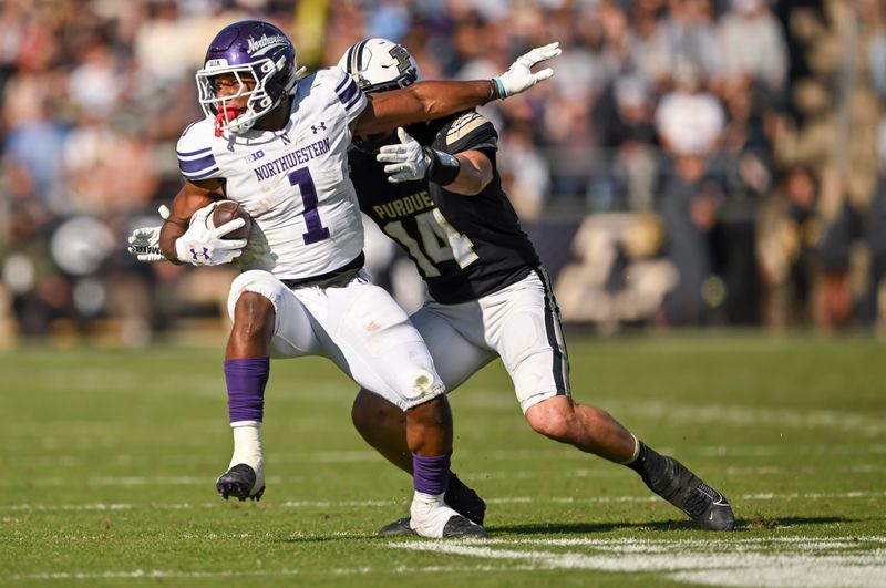 Nov 2, 2024; West Lafayette, Indiana, USA; Northwestern Wildcats running back Cam Porter (1) is tackled by Purdue Boilermakers linebacker Yanni Karlaftis (14) during the second half at Ross-Ade Stadium. Mandatory Credit: Marc Lebryk-Imagn Images