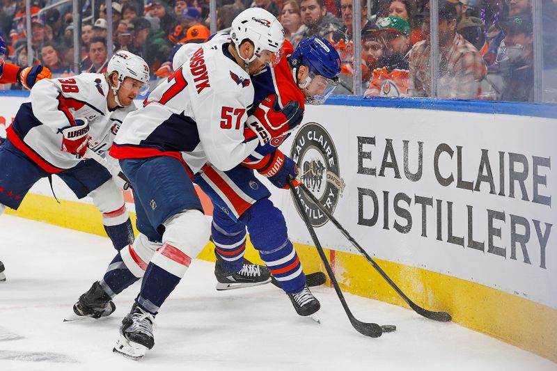 Jan 21, 2025; Edmonton, Alberta, CAN; Washington Capitals defensemen Trevor van Riemsdyk (57) and Edmonton Oilers forward Zach Hyman (18) battle along the boards for a loose puck during the third period at Rogers Place. Mandatory Credit: Perry Nelson-Imagn Images